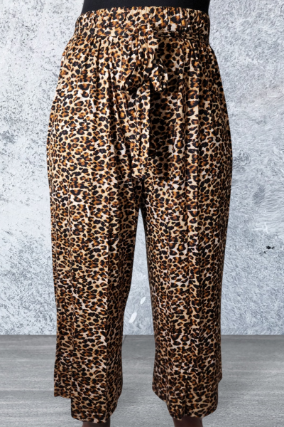 Leopard print pants on a person against a gray concrete wall.