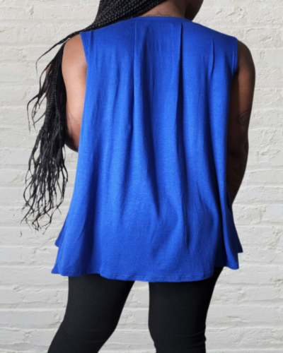 Person wearing a blue sleeveless top against a white brick wall