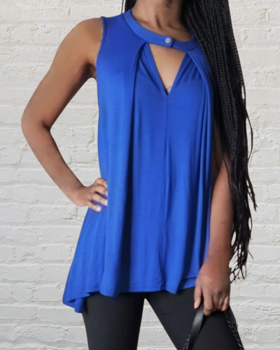 Person wearing a blue sleeveless top against a white brick wall