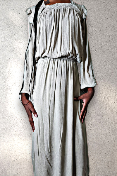 Person wearing a sage green dress with long sleeves on a textured white background