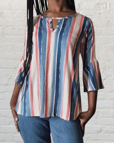 Person wearing a striped shirt with a white brick wall background