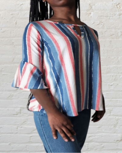 Person wearing a striped shirt and jeans against a white brick wall