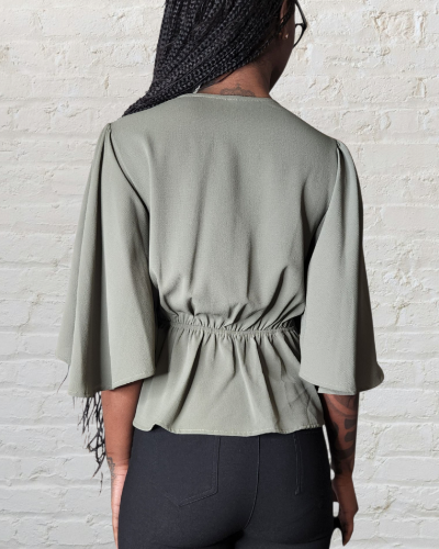 Person wearing a light green top with a white brick wall background
