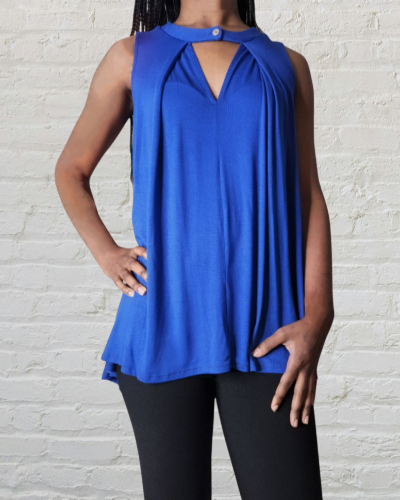 Person wearing a blue sleeveless top against a light gray brick wall.